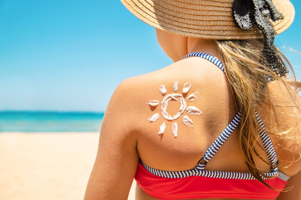 dziewczyna odpoczywająca na plaży z nakremowanymi plecami